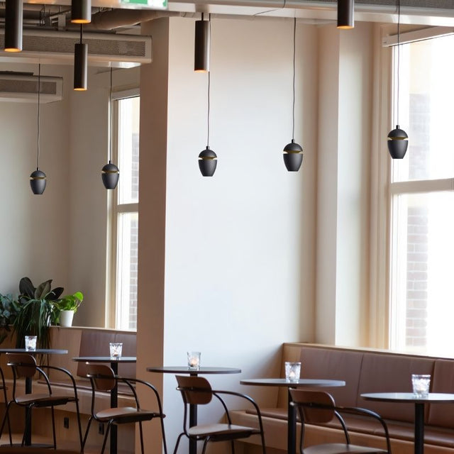 "Sleek aluminum and glass pendant light in black finish, emitting soft ambient glow, perfect for modern dining areas."