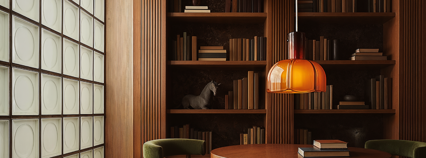 Modern interior featuring the Eloise Pendant Light with bookshelf, table, and chairs in a dimly lit room.