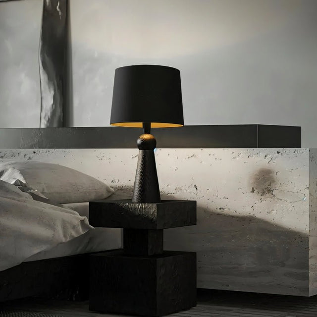 "Table lamp with a wooden base and fabric shade, placed in a contemporary bedroom, providing warm lighting, made from durable wood and fabric."