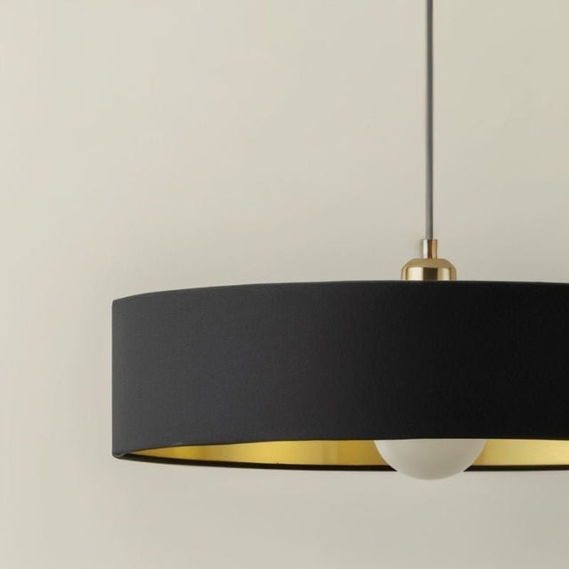 "Black fabric pendant light with gold interior, modern metallic accents, soft ambient glow, elegant design"