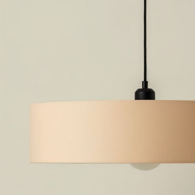 "Close-up of fabric shade with smooth finish, minimalist hanging light, black fixture detail, soft glow"