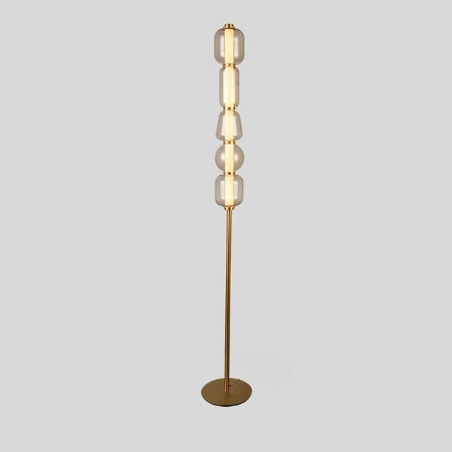 "Close-up view of the Lyris floor lamp with a gold metal base and translucent glass orbs, creating a luxurious and contemporary lighting solution. Crafted from metal, glass, and acrylic."