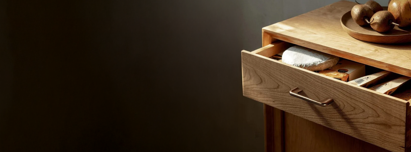Wooden drawer featuring the Nikt pull bar with items inside on a dark background.