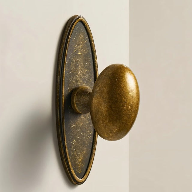 "Oval antique brass knob with backplate, featuring a smooth, ergonomic grip suitable for cabinets, drawers, and doors."