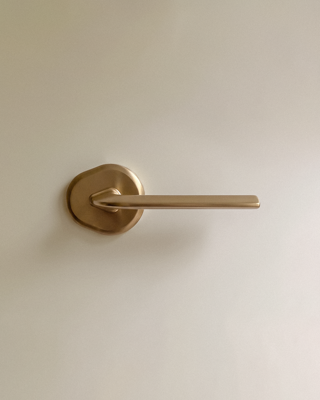 Enzo Door Handle in Satin Brass, on a plain background