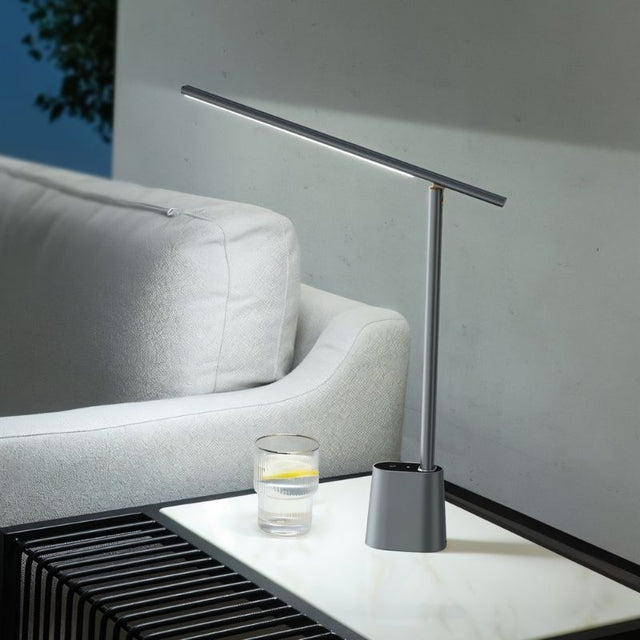 "Contemporary table lamp made of aluminum and polycarbonate on a side table, providing soft, focused light."