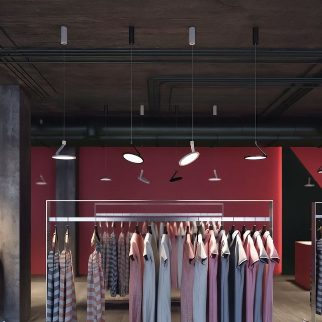 "Pendant lights in industrial retail space, circular LED panels suspended by adjustable cables, metal and plastic construction"