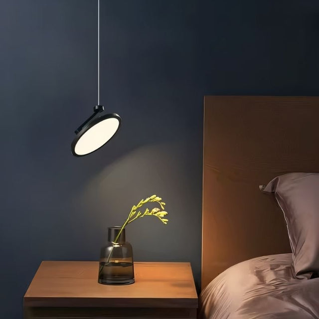 "Minimalist pendant light illuminating bedside table, circular LED panel, sleek and adjustable design, durable metal and plastic construction"