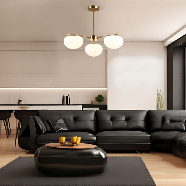 "Pendant lamp with three glass shades and a golden finish, illuminating a chic living room."