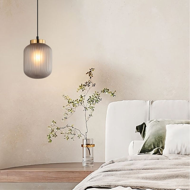 "Elegant pendant light made from glass and iron, hung above a side table in a cozy, contemporary bedroom setting."