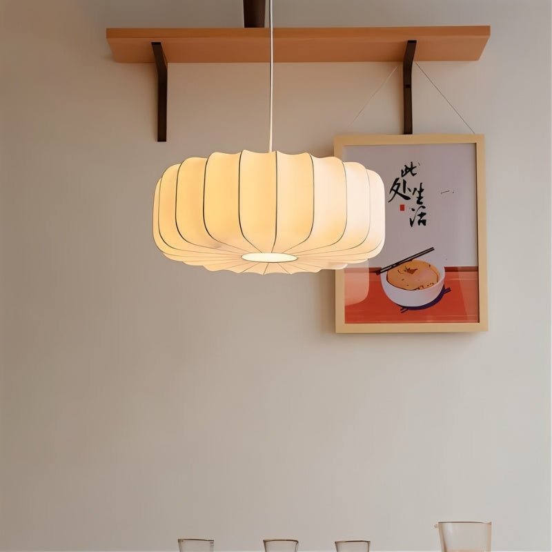 "Pendant light featuring a pleated iron and silk design, radiating a warm and sophisticated glow in a dining room setting."