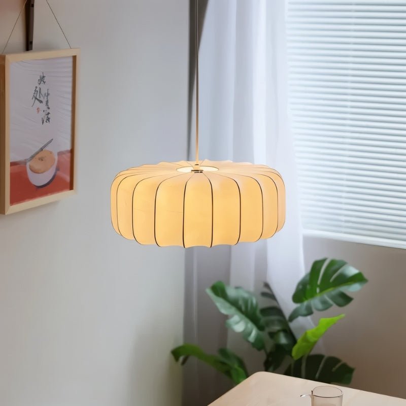 "Pleated pendant light crafted from iron and silk, gently illuminating a dining area and creating a cozy, sophisticated ambiance."