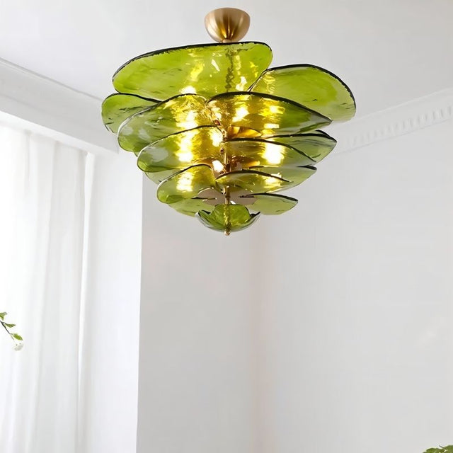 "A green Murano glass chandelier with layered petals, hanging in a room with white walls and a curtain."
