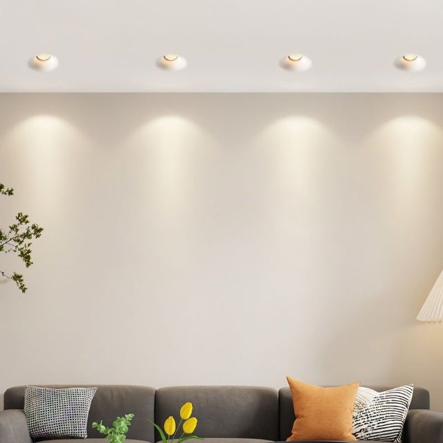 "Trimless downlights in a living room, integrated seamlessly into the ceiling with gypsum and aluminum materials, providing ambient lighting."