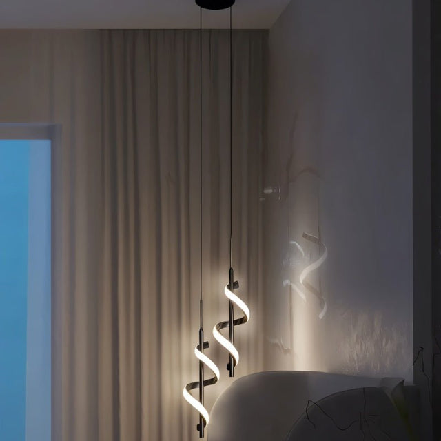 "Two black pendant lights with a spiral design, shown lit up in a bedroom with a curtain and a bed."