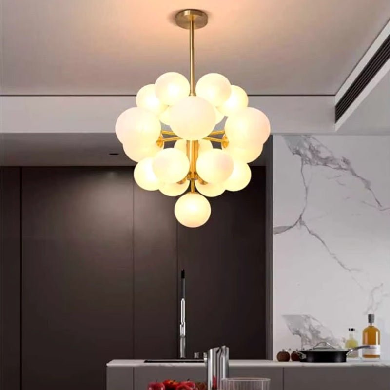 "A modern brass chandelier with frosted glass globes hanging above a kitchen island, providing soft, ambient light."