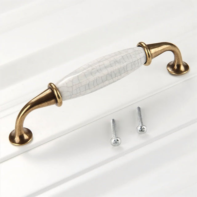"A ceramic pull bar handle with a crackled glaze and antique brass supports, shown with screws on a white surface."