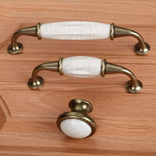 "Ceramic pull bar handles with a crackled glaze and antique brass supports, mounted on a wooden drawer."