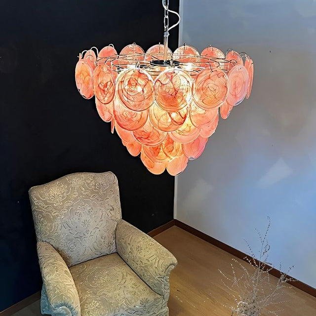 "A Murano glass disc chandelier in a room setting with a chair."