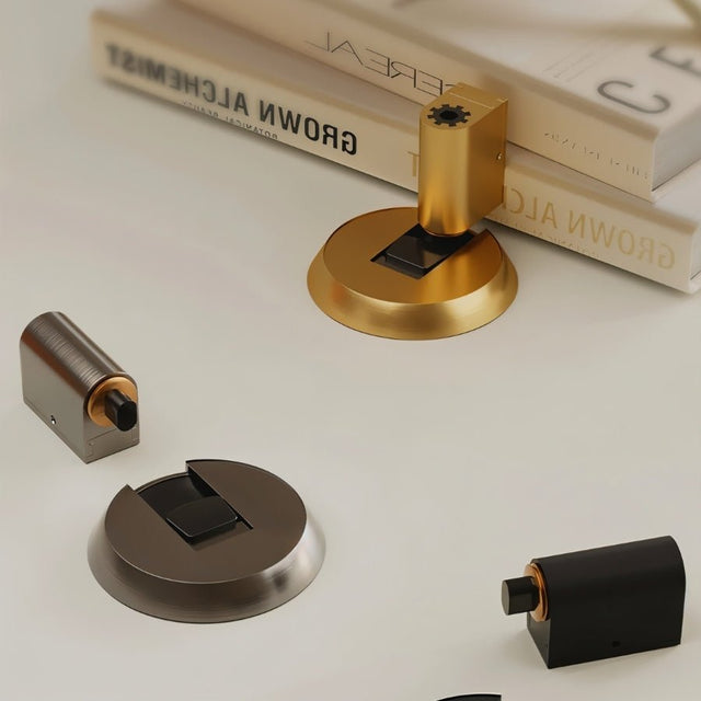 "Modern brass door stops in gold, silver, and black finishes, complementing contemporary home decor."