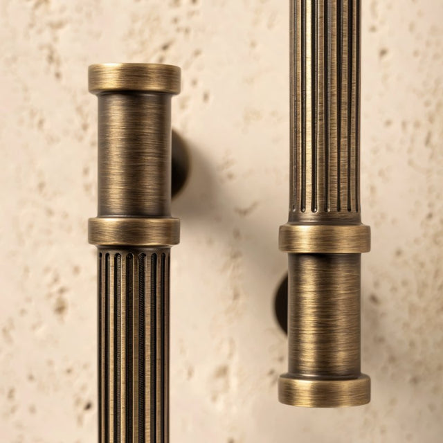 "Close-up of antique brass fluted pull bars with detailed end caps, showcasing the ribbed texture and classical design."