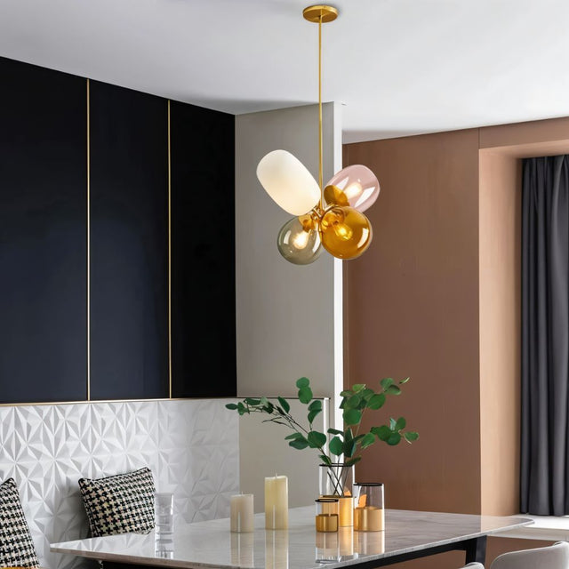 "Sculptural pendant light with a cluster of asymmetrical glass shades in warm tones hanging above a dining table."