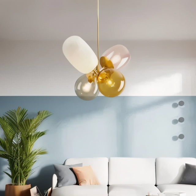 "Modern pendant light with clustered asymmetrical glass shades in warm tones over a white sofa."