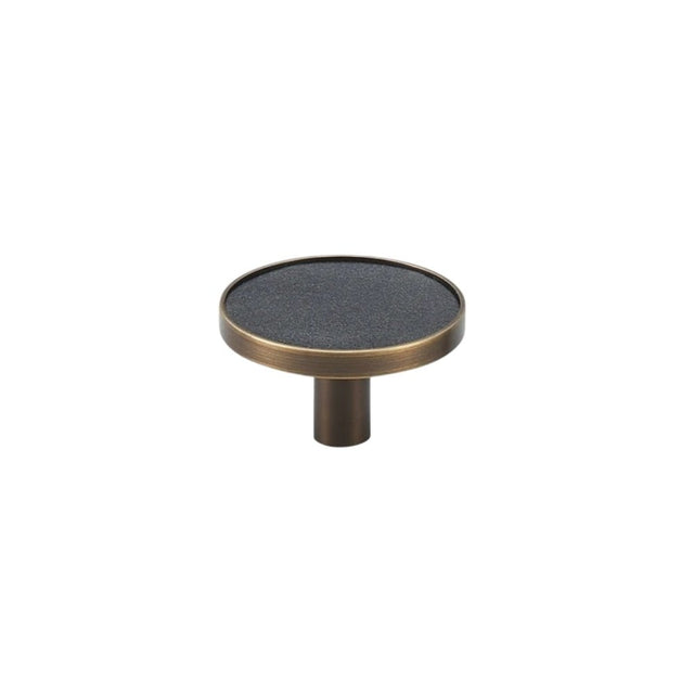 "Angled view of a black leather and brass knob with stitching detail, isolated on a white background."