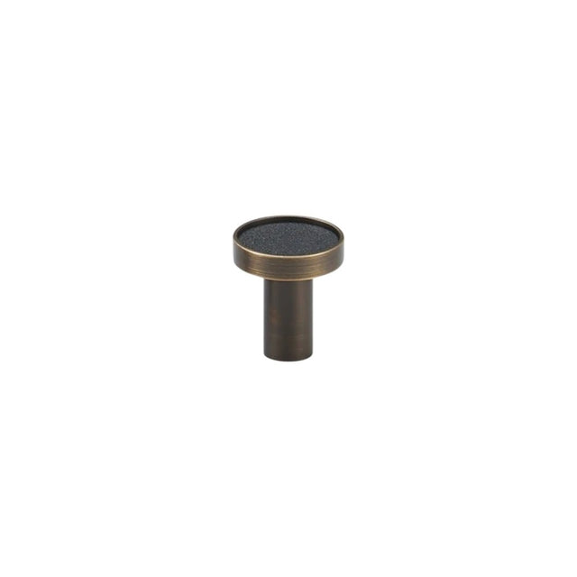"Black leather and brass knob with stitching detail, isolated on a white background."