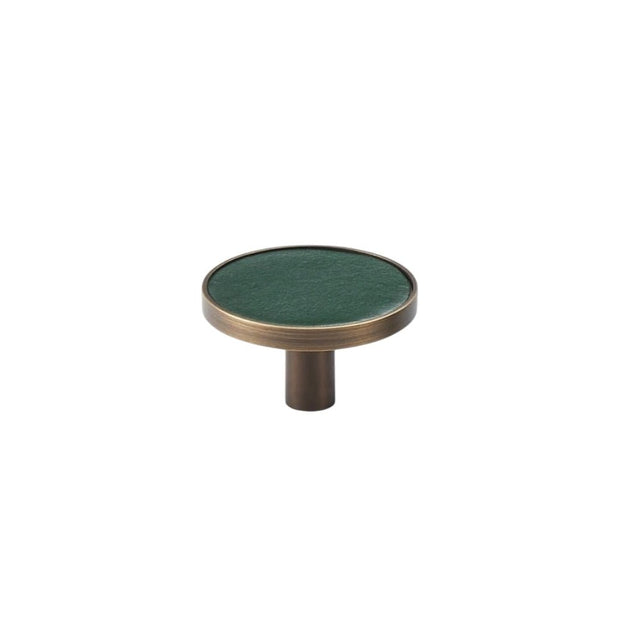 "Angled view of a green leather and brass knob with stitching detail, isolated on a white background."