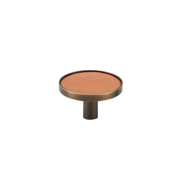 "Angled view of a tan leather and brass knob with stitching detail, isolated on a white background."
