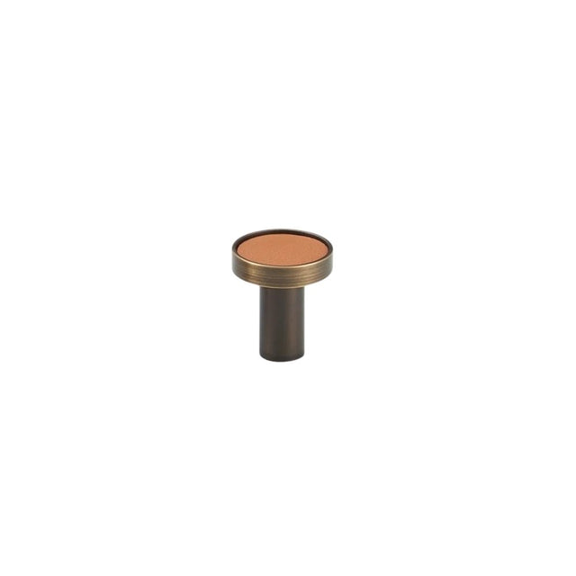"Tan leather and brass knob with stitching detail, isolated on a white background."