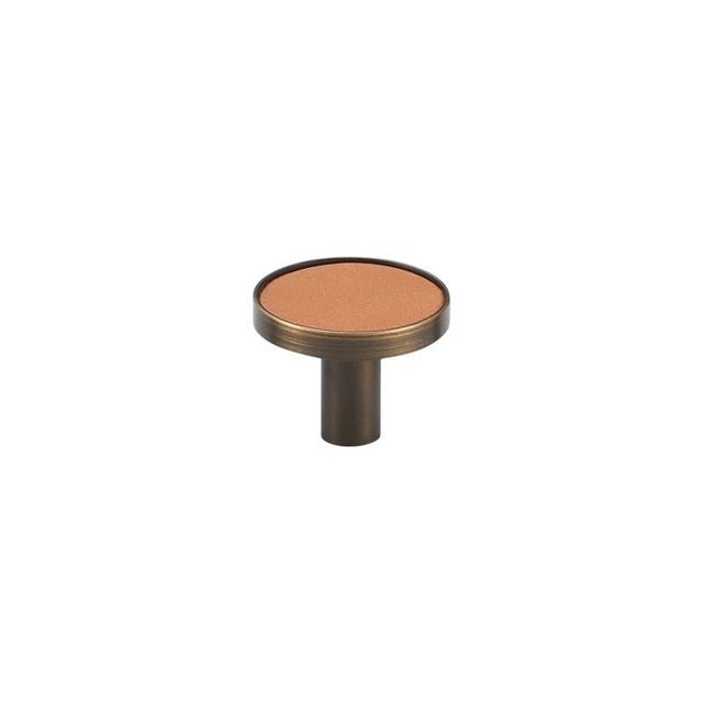 "A modern tan leather and brass cabinet knob on a white background."
