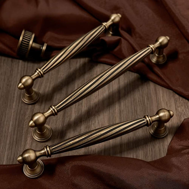 "Brass antique twisted fluted knobs and pulls on a wood background"