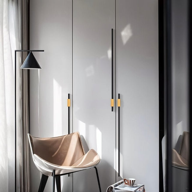 "Modern black and gold aluminum pull bars installed on a white wardrobe in a contemporary room."
