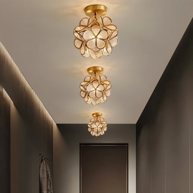 "A series of modern, floral ceiling lights with brass frames and textured glass petals, illuminating a contemporary hallway."