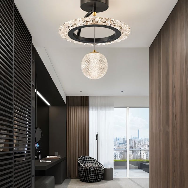 "A black ceiling light with a circular frame and a hanging crystal sphere, installed in a hallway with a dark wall panel and a view of a city."