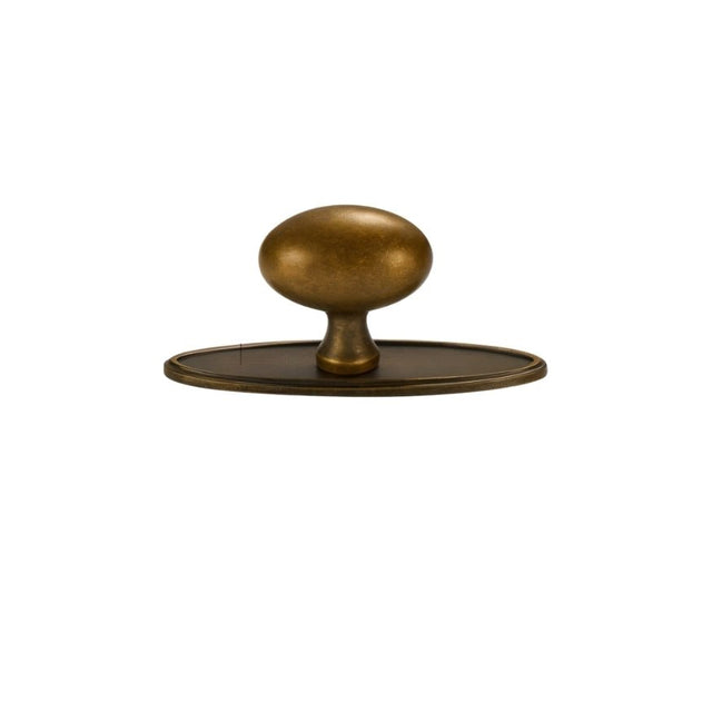 "An oval antique brass knob with a smooth, ergonomic grip, suitable for cabinets, drawers, and doors."