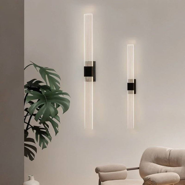 "Pair of modern acrylic wall sconce lights with a minimalist design on a light-colored wall."