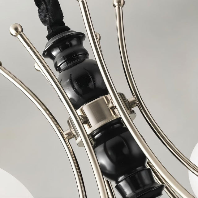 "Close-up detail of a modern chandelier showing curved metal arms and a black central column."