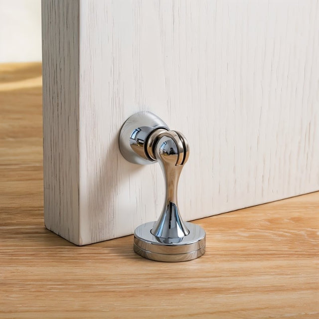 "Sleek, zinc-alloy magnetic door stop with a contoured design, installed on a door, preventing it from slamming and protecting the wall in a modern interior."