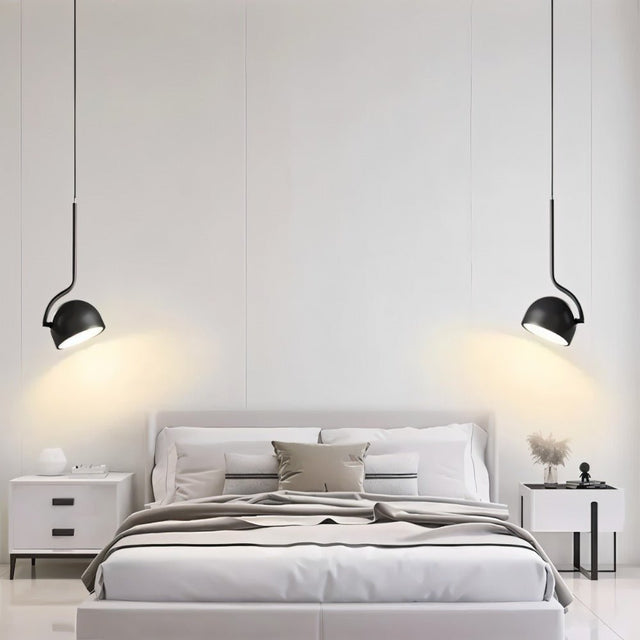 "Two black pendant lights with curved iron fixtures and dome-shaped shades flank a modern bed, providing focused illumination."