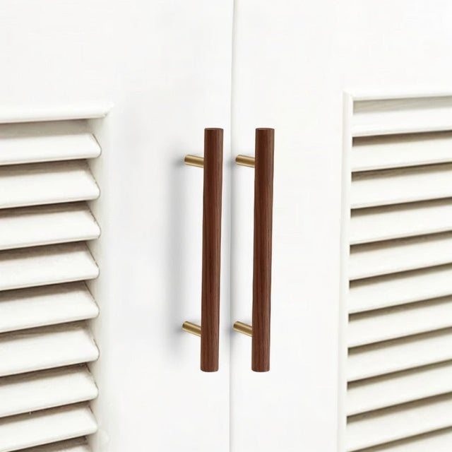 "Modern wooden cabinet pull handles with brass accents on white shaker-style cabinets."