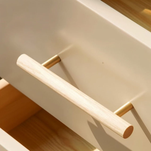 "Close-up of a modern wooden drawer pull handle with brass hardware on a light-colored drawer."
