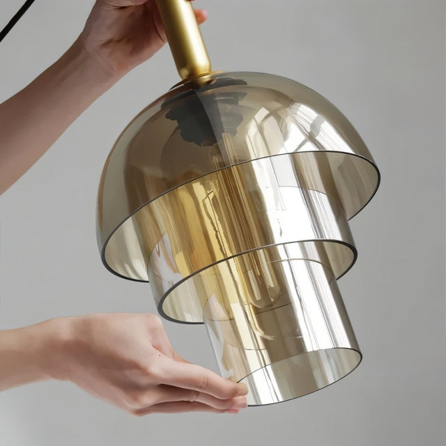 "Close-up detail of a modern pendant light showing layered smoked glass and a metallic accent."