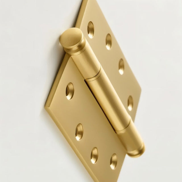 "Close-up of a polished solid brass barrel hinge with decorative finials, showing the eight-hole mounting plate."