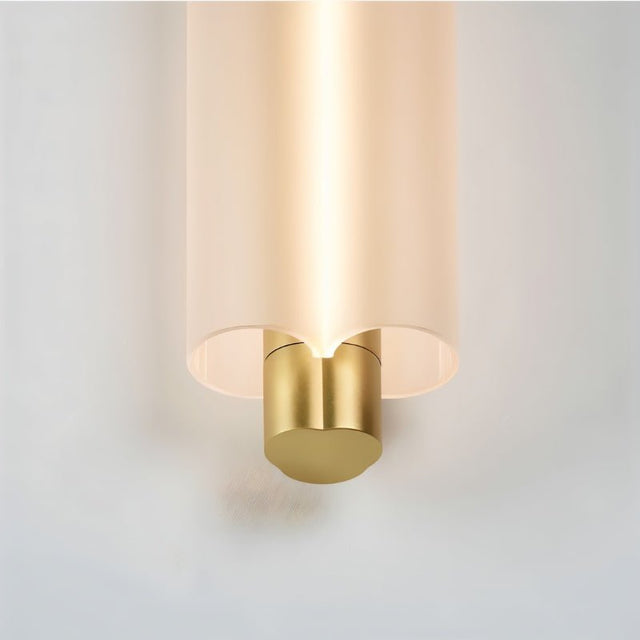 "Close-up of a minimalist pendant light showing the frosted acrylic cylinder and brass details, with a warm light glowing from within."