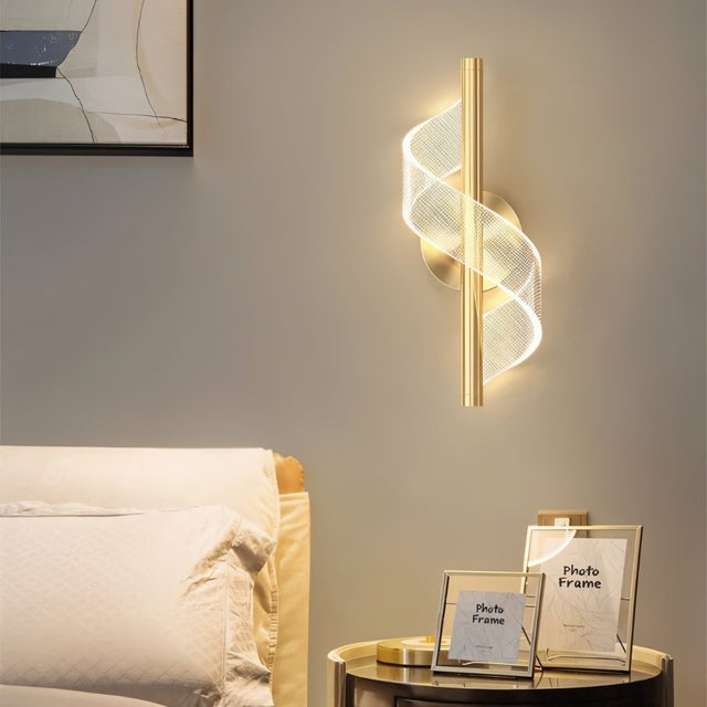 "Modern sculptural wall lamp with a spiral acrylic diffuser and golden finish, providing ambient light as a bedside sconce in a contemporary bedroom."