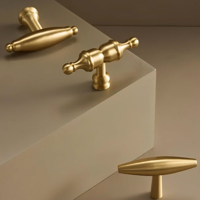 "Brass cabinet knobs with a sculptural design, shown from various angles to highlight their elegant curves and polished finish."