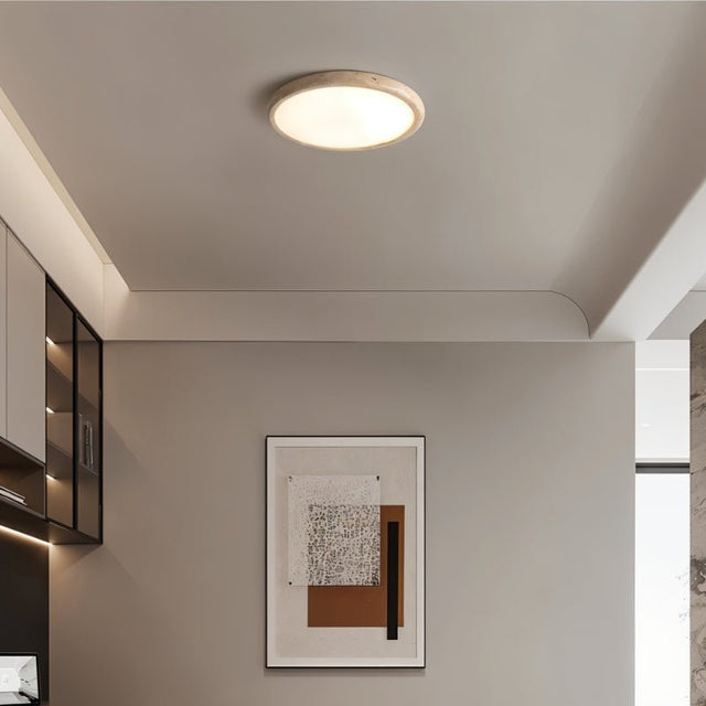"Modern flush mount ceiling light with a circular yellow travertine frame and a white acrylic diffuser, providing ambient lighting in a contemporary space."